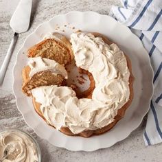 a white plate topped with a cake covered in frosting next to a bowl of whipped cream