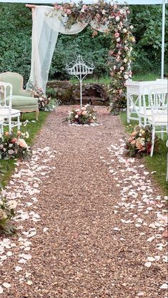 an outdoor wedding ceremony with white chairs and petals on the ground in front of it