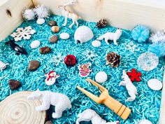 a wooden box filled with lots of different types of toys and decorations on top of blue rice