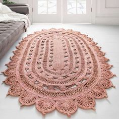 a pink crocheted rug on the floor in front of a couch and window