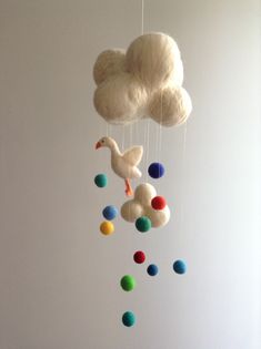 a white cloud mobile with colorful balls hanging from it's sides and a duck on the other side