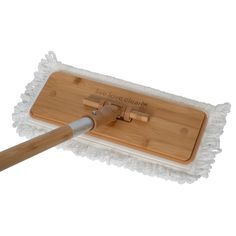 a mop with a wooden handle on top of a white cloth covered flooring pad