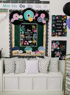 a white bench sitting in front of a wall with pictures and pillows on it's sides