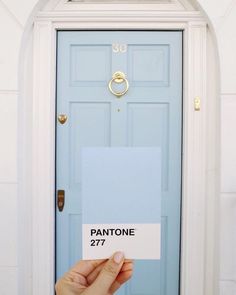 a person holding up a sign in front of a blue door that says pantone