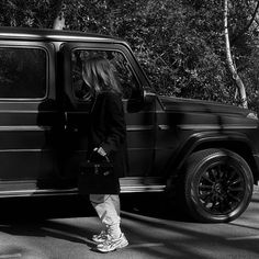 black and white photograph of a woman standing in the door of a mercedes g class