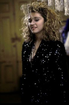 a woman with curly hair standing in front of a chandelier