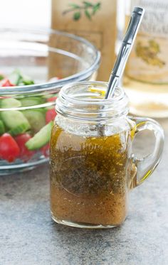 a glass jar filled with liquid next to a bowl of vegetables