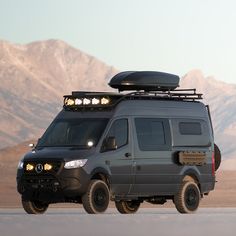 the van is parked on the side of the road with mountains in the back ground