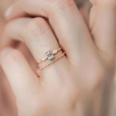 a woman's hand with two gold rings on it and one diamond ring in the middle