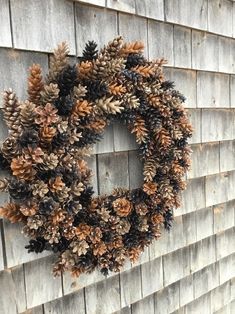 a wreath made out of pine cones is hanging on the side of a house wall