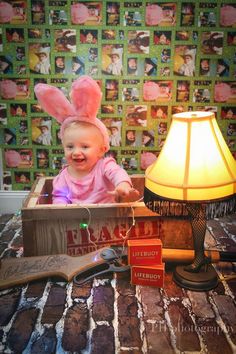 a baby sitting in a box on top of a table next to a lamp and some books