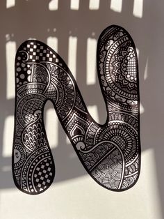 the letter n is made up of intricately designed paper and has a shadow cast on it