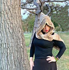 a woman standing in front of a tree wearing a hat and scarf on her head