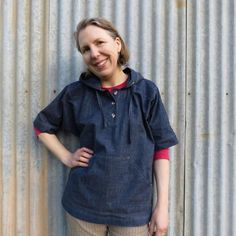 a woman standing in front of a metal wall with her hands on her hips and smiling