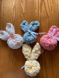 four crocheted easter bunnies with bows on them sitting on top of a wooden table