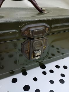 an old green suitcase sitting on top of a polka dot table