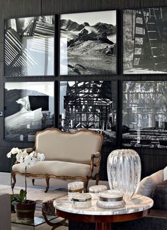 a living room filled with furniture and pictures on the wall next to a table in front of a window