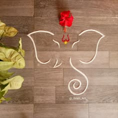 an elephant drawn on the floor next to a potted plant with a red ribbon