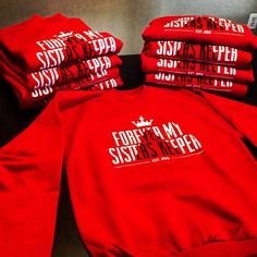 red sweatshirts with white lettering on them sitting next to each other in a pile