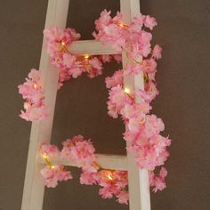 a ladder decorated with pink flowers and fairy lights on the bottom part of its frame