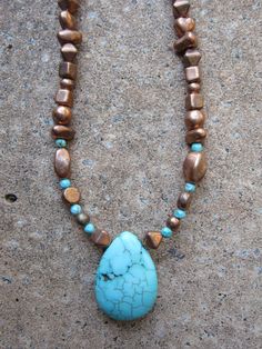 a necklace with a turquoise and brown bead on it's end is laying on the ground