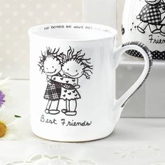 two coffee mugs sitting next to each other on a table with flowers in the background