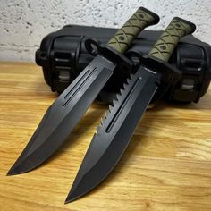 two knives sitting next to each other on top of a wooden table in front of a black case