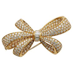 Dating from circa 1997, this 18K gold Tiffany & Co. bow brooch is set with over 7 carats of diamonds. It is designed as a highly three dimensional bow of five loops pavé-set throughout with round brilliant-cut diamonds, its center channel-set with a band of graduating diamond baguettes. Sculptural and densely packed with vibrant diamonds, this beautifully-made bow is a classic, eternally chic Tiffany jewel. Product Details: Item #: BO-21187 Artist: Tiffany & Co. Country: Italy Circa: 1997 Dimensions: 2.50" length x 1.25" width Materials: 7 baguette diamonds (approximate total weight 0.49 carat); 227 round diamonds (approximate total weight 6.80 carats); 18K Gold Signed: TIFFANY & CO, ITALY, 750, 12975511 Literature: A brooch of this design is pictured in Tiffany's 20th Century: A Portrait Jewelry Illustration, Diamond Bows, Gold Sign, Tiffany And Co, Tandem, Baguette Diamond, Round Brilliant Cut Diamond, High Jewelry, Tiffany & Co.