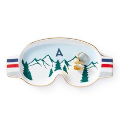 a pair of glasses sitting on top of a plate with mountains and trees painted on it