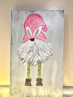 a painting of a gnome wearing a pink hat and green leggings, standing in front of a white wall