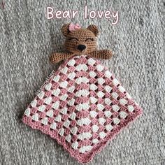 a crocheted teddy bear laying on top of a blanket