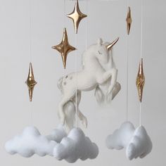 a white unicorn mobile with gold stars hanging from it's sides in the sky