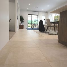 an empty living room and dining area with large tiles on the floor in front of glass doors