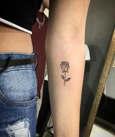 a woman's arm with a small rose tattoo on the left side of her right arm