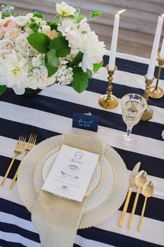 the table is set with blue and white striped linens, gold place settings, and candles