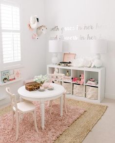 a white table and chairs in a room with pink rugs on the floor next to a window