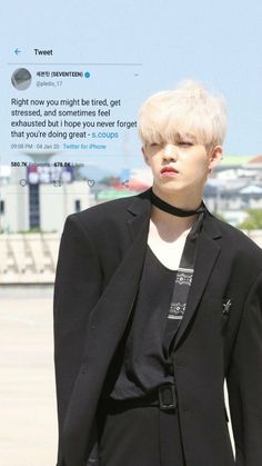 a man with white hair wearing a black suit and tie standing in front of an airport