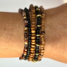 This beautiful bracelet stack pairs classic black with shades of golds, browns, and ambers for a timeless combination perfect for dressing up or going casual. Switch it up by rearranging them, or add them to some of your existing favorites for a new twist on your accessorizing.   Included are five individual stretch bracelets: black and gold; caramel and chocolate; multi brown and amber; wood; and solid black. As a handmade item, each set will vary slightly due to randomization of the multi bead patterns. Giving as a gift? The 7" size is considered "standard" and fits a lot of teens and adults. Treating yourself? Measure your wrist to choose your desired size. Selecting a set that's a little larger means the stack will slouch down on your wrist, and just right or smaller will fit more snug Brown Stackable Beaded Bracelets Gift, Gift Stackable Brown Beaded Bracelets, Brown Spiritual Bracelet With Spacer Beads, Gift Brown Stackable Beaded Bracelets, Spiritual Brown Bracelet With Spacer Beads, Black Bohemian Stretch Bracelet Stackable, Elegant Brown Beaded Bracelets With Black Beads, Adjustable Brown Stackable Jewelry, Black Bohemian Stackable Stretch Bracelet