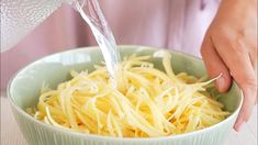 someone is pouring water into a bowl of pasta with parmesan cheese on top