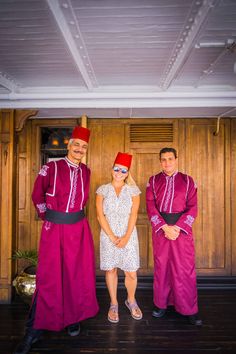 two men and a woman standing next to each other in front of a wooden wall