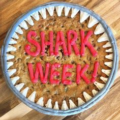 a cookie with the words shark week written on it in red icing and white cupcake liners