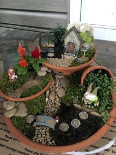 three clay pots filled with plants and small gnome figurines on top of each other