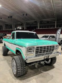 an old pick up truck is parked in a garage with other cars and trucks behind it