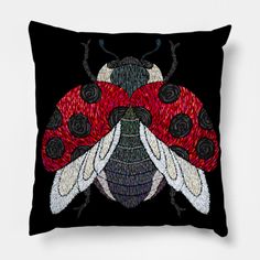 a black and red pillow with a ladybug on it