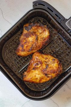 a roasted chicken in a black pan on a white wooden table