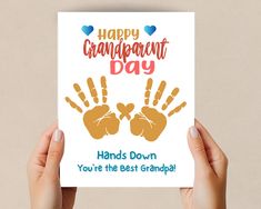 two hands holding up a card that says happy grandparents day