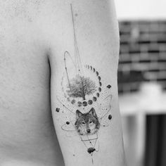 a black and white photo of a wolf tattoo on the left side of the arm