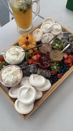 an assortment of fruits and dips on a platter next to a glass of orange juice