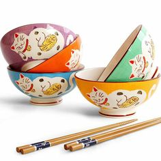 three bowls with chopsticks in front of one bowl and the other has cats on it