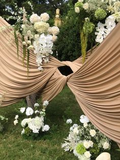 an arrangement of flowers and greenery is arranged in the shape of a heart with draping